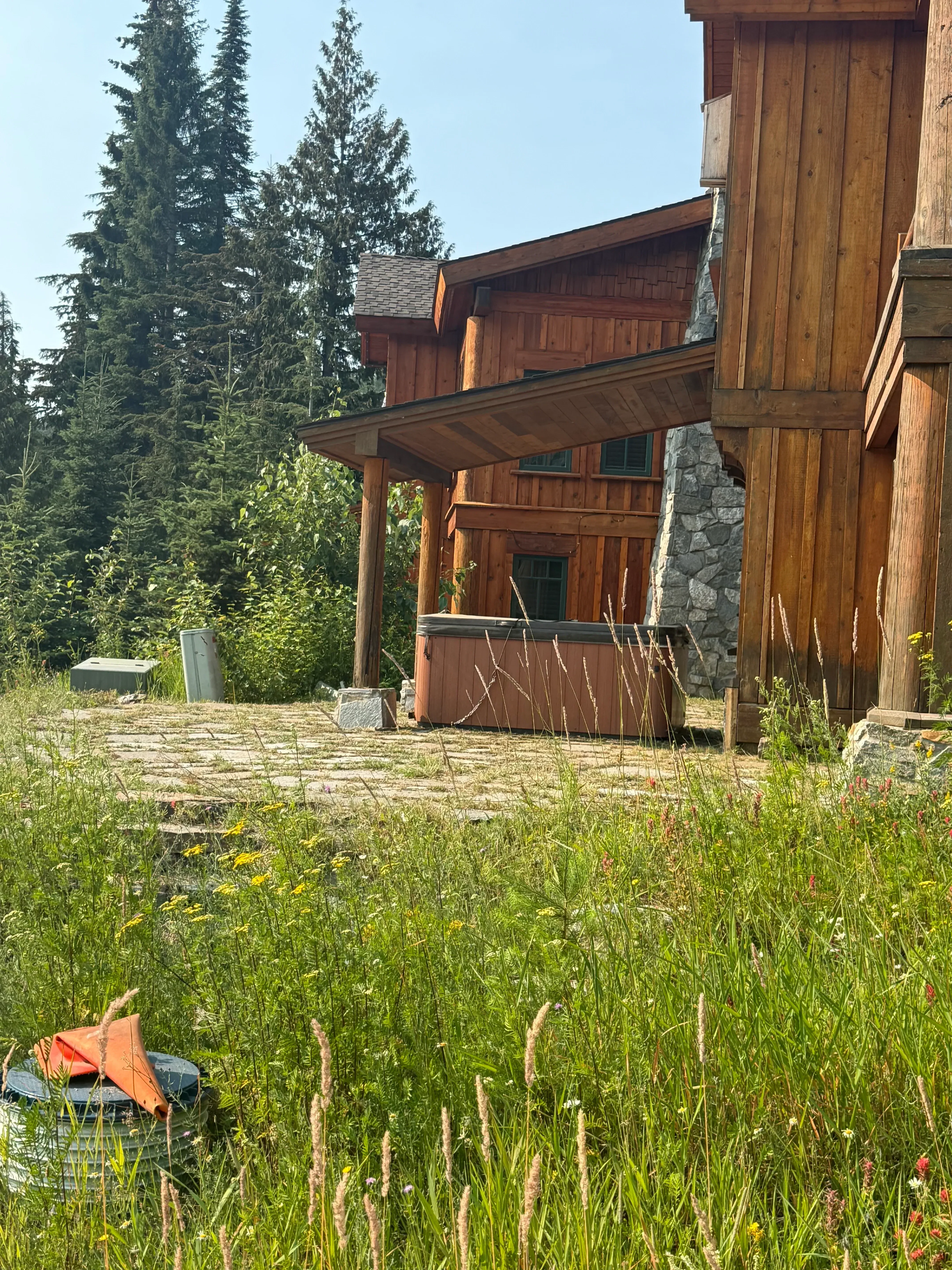 Restored log cabin with new wooden deck, stone chimney, and horizontal log siding