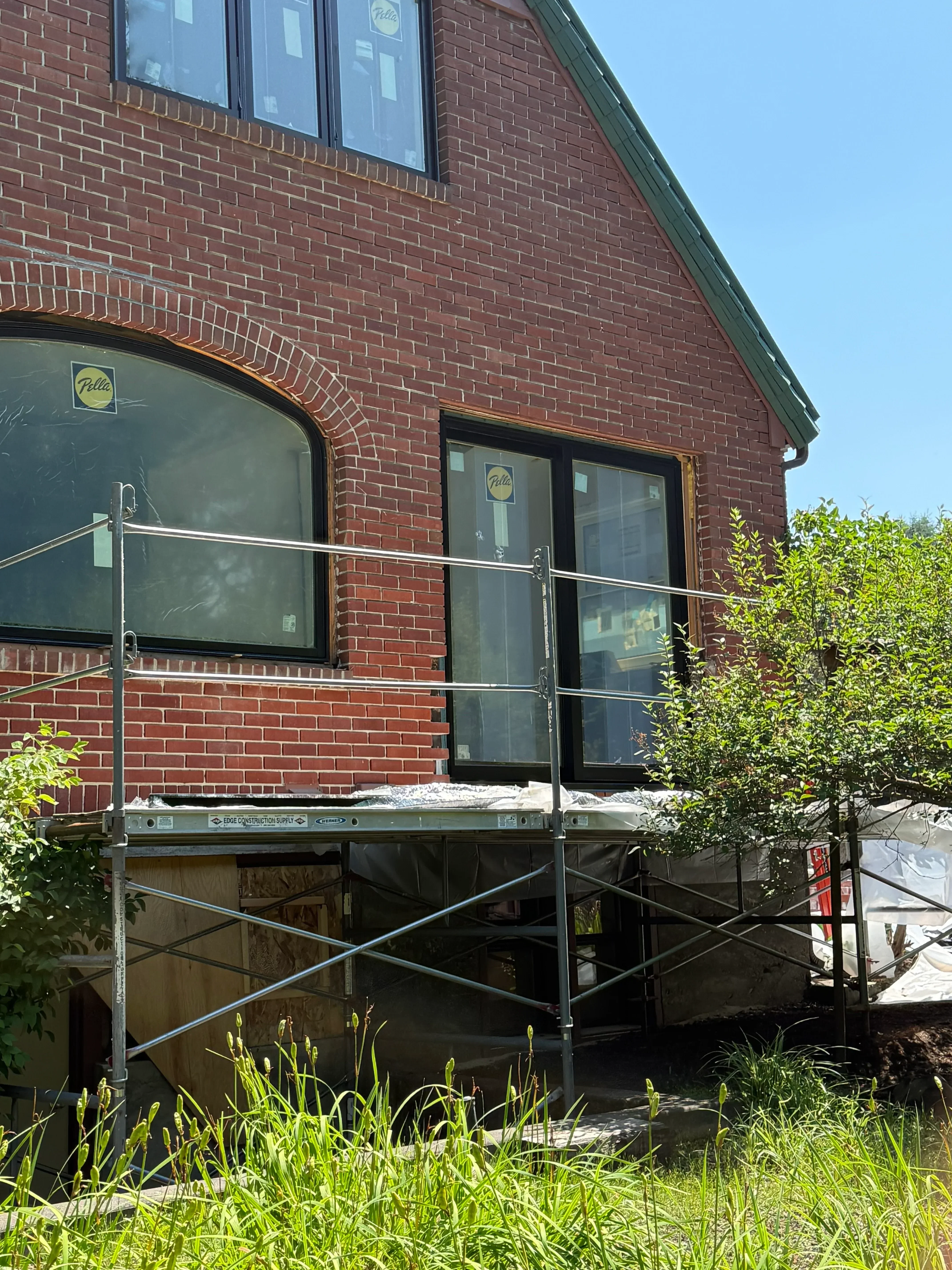 Brick facade restoration with new windows and metal scaffolding on residential building